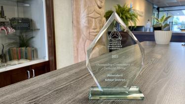 Clear glass award sits on table with front reception of district building in background