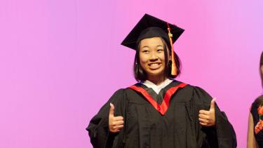 WJ Mouat Grad gives thumbs up in cap and gown