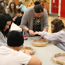 Two Indigenous Education staff members support 3 grade 5 students with their drums