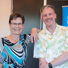Female retiree stands with male retiree, smiling for posed photo