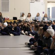Students sitting on the floor and parents/staff sitting in chairs at assembly