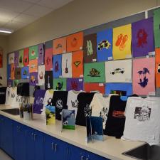 Graphic T's set up for Art show. Students walking around looking at art pieces