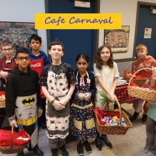 A group of students holding baskets with goodies and wearing aprons.