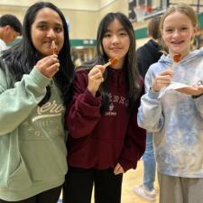 Three students standing, holding a sweet treat from the "Maple Man"