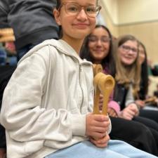 Student sitting holding wooden spoons instrument