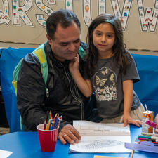 Parent siting with young student looking at school work